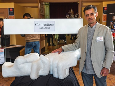 Peter Jeffries – a man standing next to a white sculpture of large hands, in the foyer of City Hall